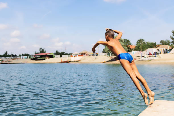istock Small boy jumping in the water from a pier. 1302829494