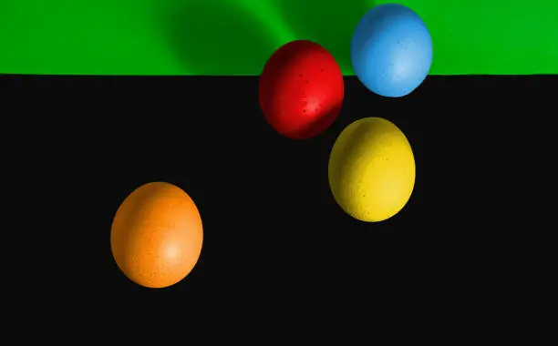 Abstract picture at Easter, four eggs from a predominantly black and in the upper part green background, concept