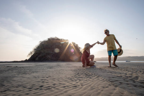 istock Mature couple relaxes on sandy beach at sunrise 1302831369