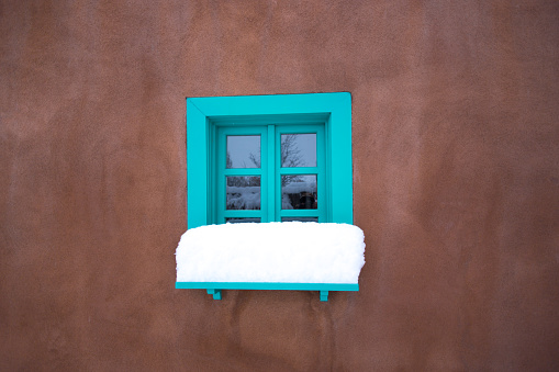 Santa Fe, NM: Traditional Turquoise Window, Adobe Wall, Snow. Copy space available.