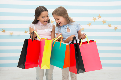 Discount concept. Kids cute girls hold shopping bags. Shopping discount season. Spending great time together. Children satisfied shopping striped background. Obsessed with shopping and clothing malls.