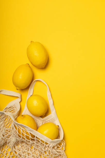 istock Eco-friendly bag with ripe yellow lemons on yellow background 1302835424