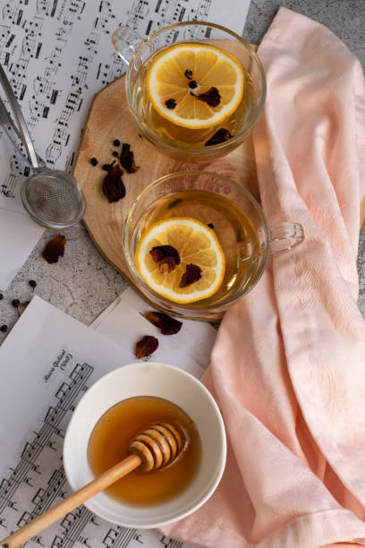 istock Cup of lemon tea and honey on grey background with music note sheets 1302838188