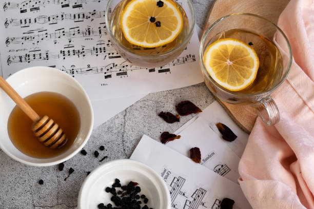 istock Cup of lemon tea and honey on grey background with music note sheets 1302838189