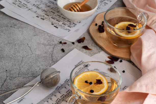 istock Cup of lemon tea and honey on grey background with music note sheets 1302838194