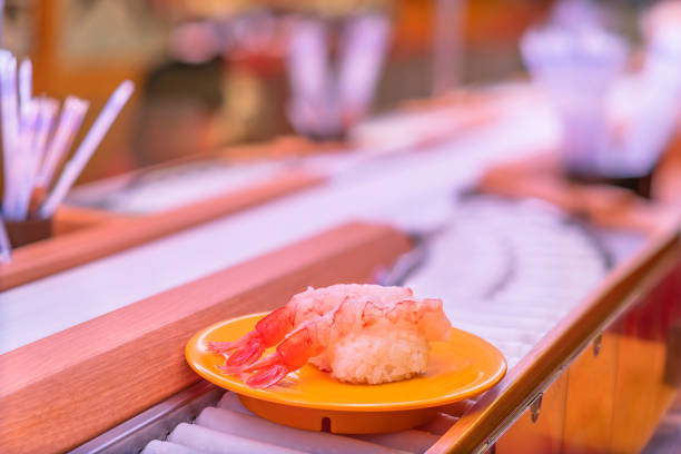 plato de dos piezas de sushi de camarones tempura en una cinta transportadora. - sushi lifestyles japanese culture freshness fotografías e imágenes de stock