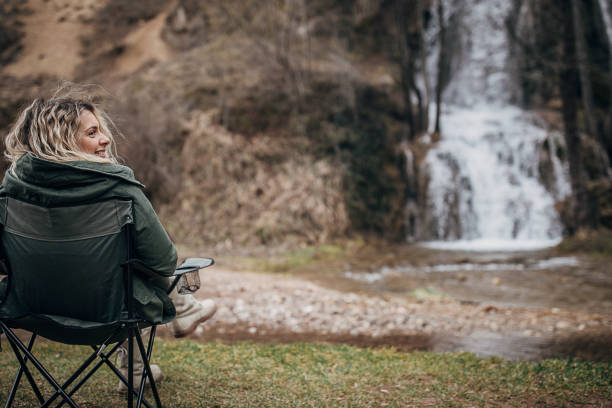 istock Woman sitting by waterfall in nature 1302846086