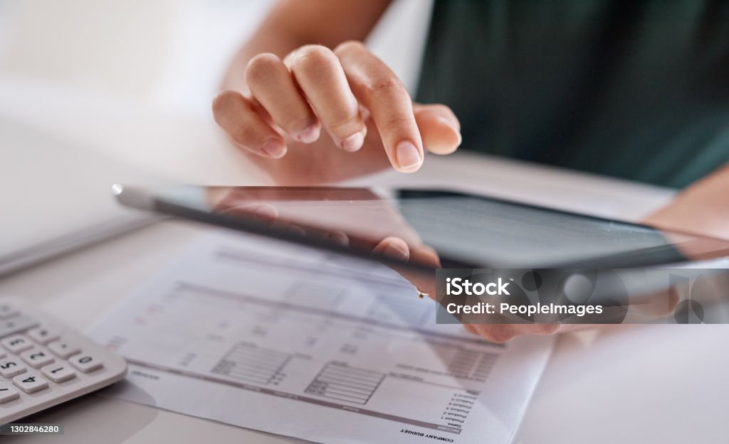 Technology greatly assists with all her duties Closeup shot of an unrecognisable businesswoman using a digital tablet while going through paperwork in an office Tax Stock Photo