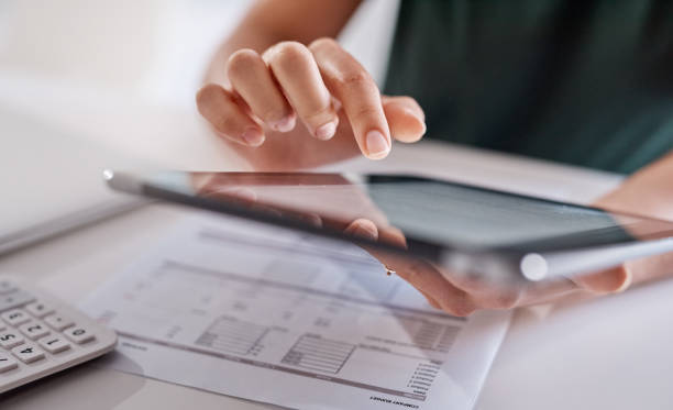 Technology greatly assists with all her duties Closeup shot of an unrecognisable businesswoman using a digital tablet while going through paperwork in an office audit stock pictures, royalty-free photos & images