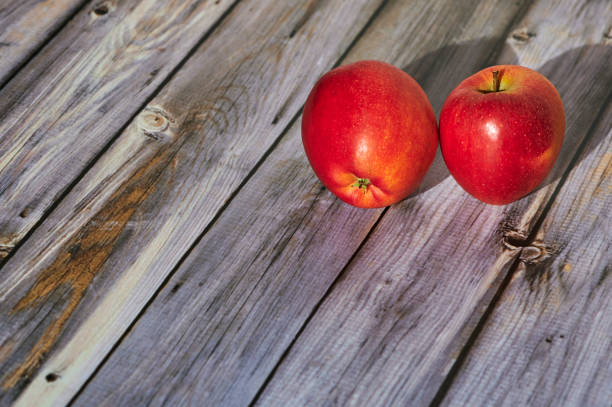 Apples lit from the sun decoratively lying on a wooden underground.