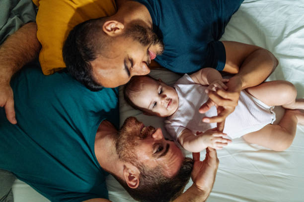 Homosexual couple enjoying time at home with adopted baby Gay couple adopted baby girl and enjoying the parenthood gay person stock pictures, royalty-free photos & images