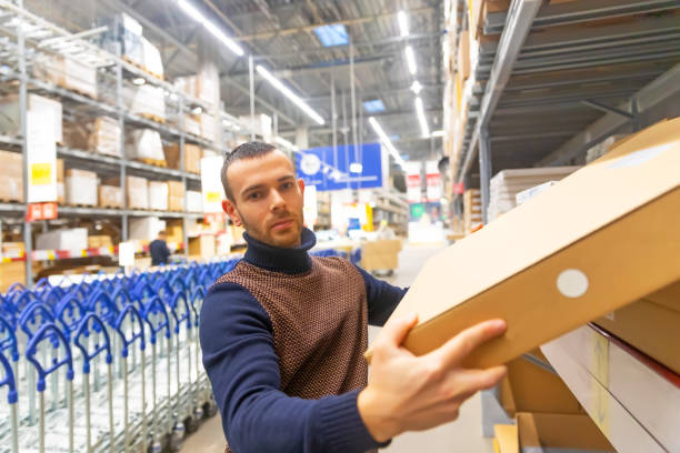 istock Young man takes a flat box with shelf goods in a large store warehouse. 1302852817