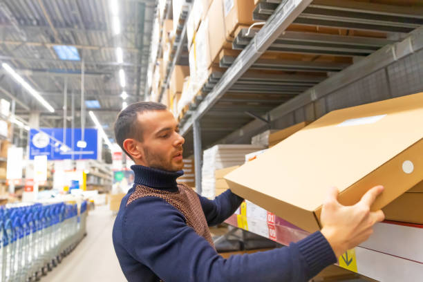 istock Young man takes a flat box with shelf goods in a large store warehouse. 1302852830