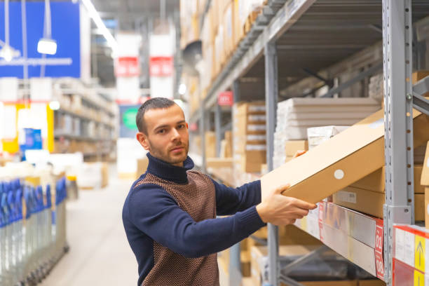 istock Young man takes a flat box with shelf goods in a large store warehouse. 1302852836