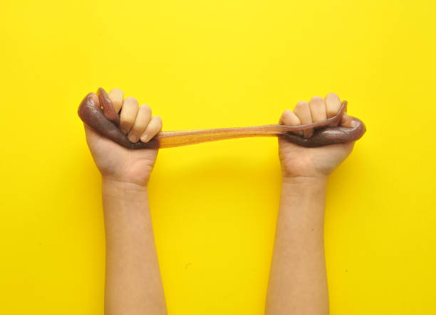 istock Child hands with slime on yellow background. 1302853102