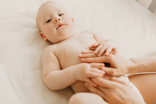 baby massage, mom massages the baby's belly during colic - colic imagens e fotografias de stock