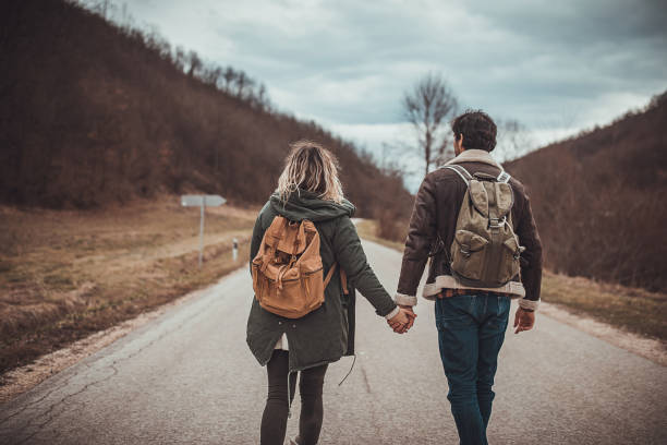 istock Couple hikers walking on the road 1302856664