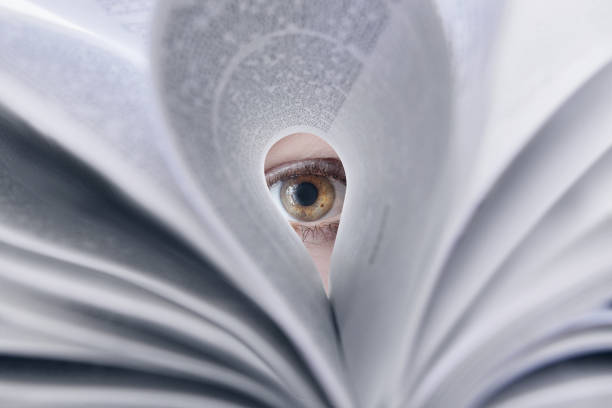 The concept of looking at everything based on knowledge. The concept of looking at everything based on knowledge. The concept of gaining knowledge . The eye looks through a sheet of textbook. peeking human eye paper eyeball stock pictures, royalty-free photos & images