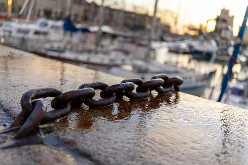 Close-up of a chain in la rochelle harbor. Boats in the background are very blurry.
