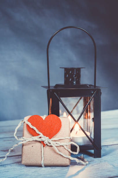 istock handmade gift with a red heart attached. an illuminated lantern in the background. eco friendly concept 1302866974