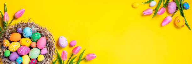 pasen - verfraaide eieren in nest met roze tulpen op gele achtergrond - easter stockfoto's en -beelden