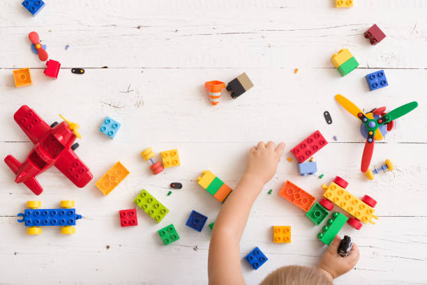 istock Top view on child playing and building with colorful plastic bricks at white wooden table. Early learning and development. 1302869760