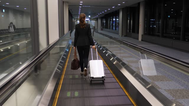 Woman walk on travelator at empty passage of airport after flight