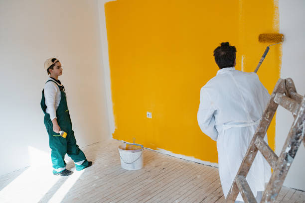 father and son decorating and painting wall in yellow color with paint roller. - house painter paint roller yellow painting imagens e fotografias de stock