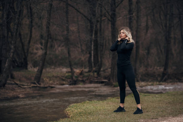 One woman, beautiful fit young woman standing by the river alone in nature.