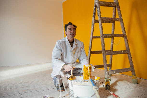 istock Painter and decorator mixing yellow paint in the bucket 1302873888