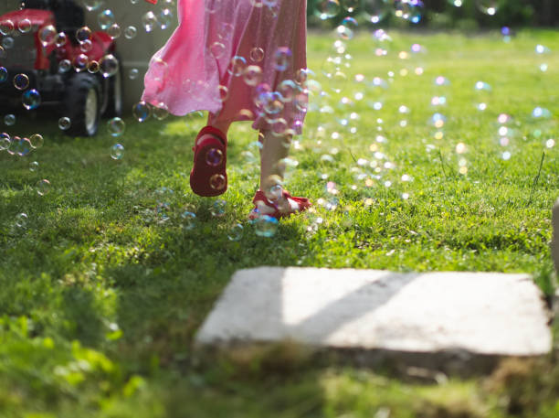 Little Girl in Pink Dress Running Through Soap Bubbles in the Yard