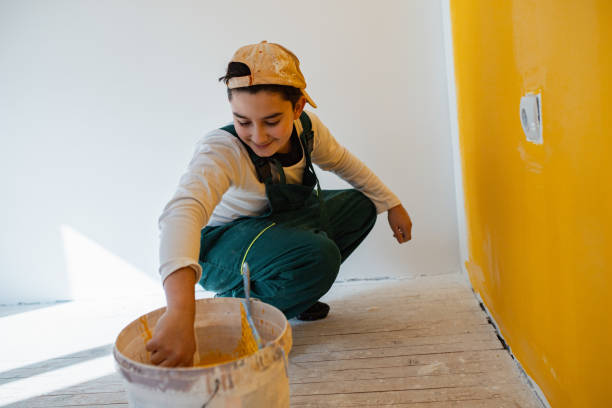istock Young boy in work wear taking paint from utensil 1302875665