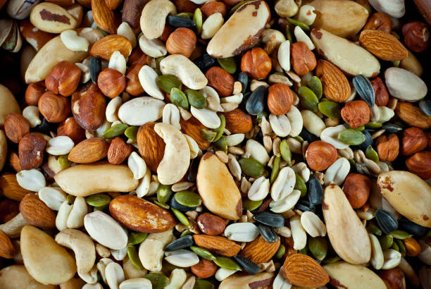 istock Many types of nuts close up. Textures of different nuts. Nuts are dumped in a pile. Contrasting dramatic light as an artistic effect. 1302875686