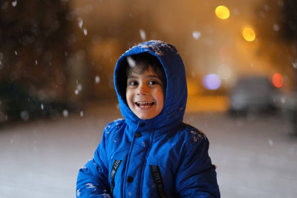 istock Preschool boy playing in the snow at night. 1302883768