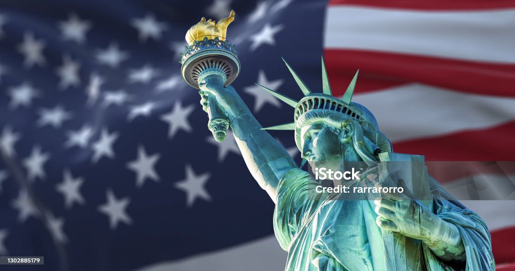 the statue of liberty with the blurry american flag waving in the background the statue of liberty with the blurry american flag waving in the background. Democracy and freedom concept Statue of Liberty - New York City Stock Photo