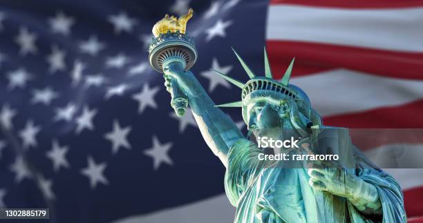 The Statue Of Liberty With The Blurry American Flag Waving In The Background Stock Photo - Download Image Now