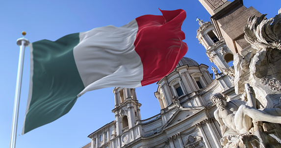 The italian flag flapping with The fountain of the four rivers with the facade of the church of Santa Agnese in Piazza Navona in Rome. Town square. Baroque art. Tourism and travel
