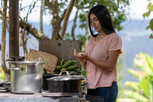 Colombian woman living in the countryside and making arepas for breakfast in a rustic kitchen at a farm - lifestyle concepts