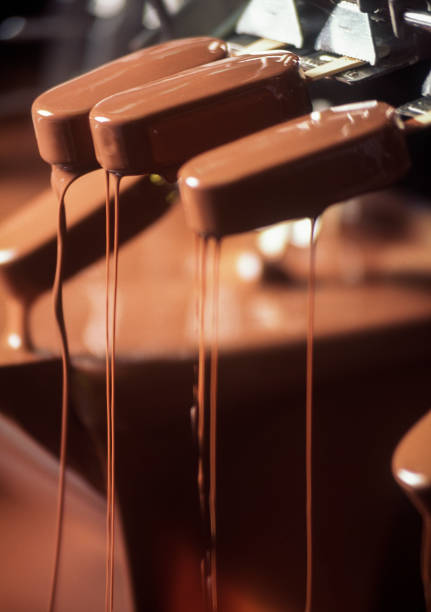 Vanilla Popsicle being dipped in chocolate in ice cream factory