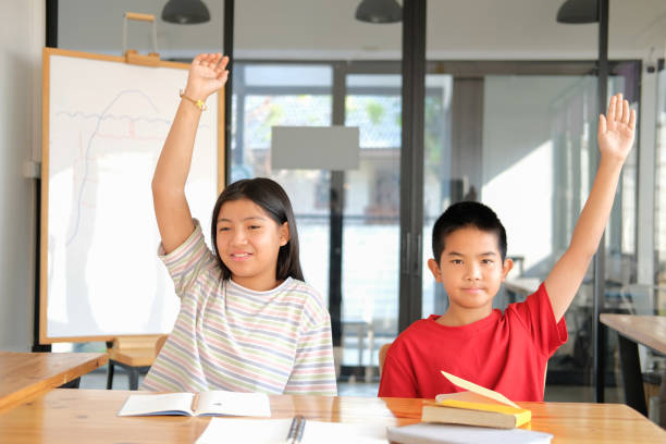 istock girl boy student studying raising hand in classroom. learning education at school 1302891254
