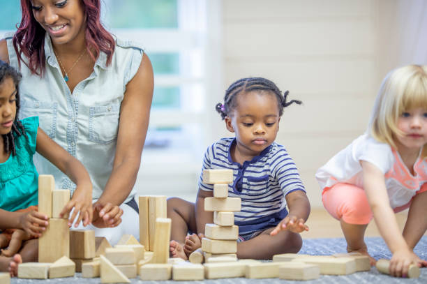 istock Preschool teacher playing with blocks with her students 1302891452