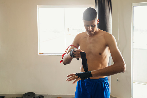 sporty male boxer in blue gloves practicing punches on a light background cropped view. High quality photo