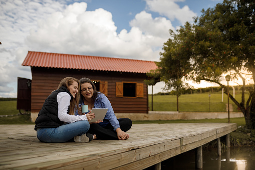 Two women watching video on tablet at cabin deck