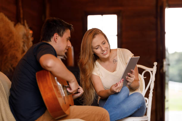 istock Couple playing guitar using tablet at cozy cabin 1302894445
