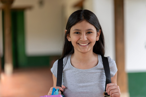 Portrait of a Latin American girl looking very happy to go back to school and looking at the camera smiling - education concepts