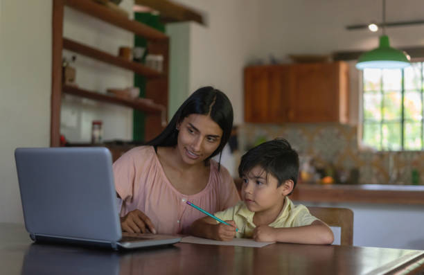 madre supervisando a su hijo mientras estudia en línea desde casa usando una computadora portátil - farmer rural scene laptop computer fotografías e imágenes de stock