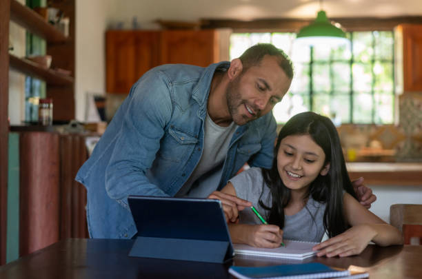 istock Father helping his daughter while studying online at home 1302894573