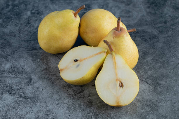 istock Whole and half cut yellow pears on the grey marble background 1302894921