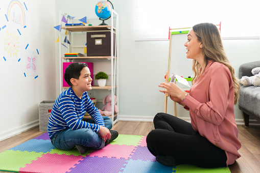 LIttle boy with language problems receiving speech therapy with a female child therapist at her office