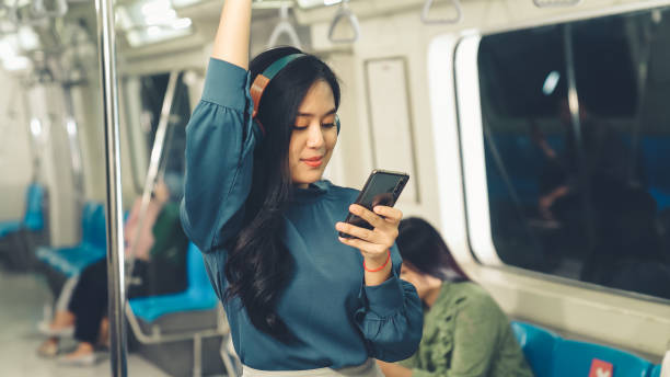 istock Young woman using mobile phone on public train 1302899575